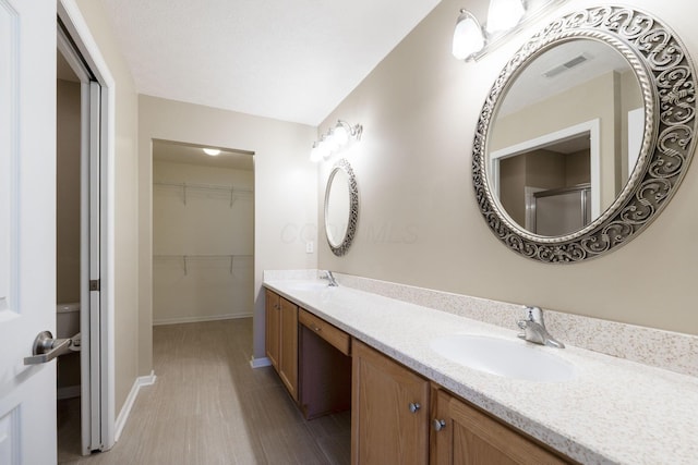 bathroom with a shower with shower door, toilet, and vanity