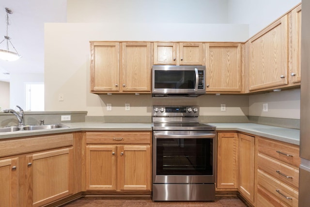 kitchen featuring stainless steel appliances, light brown cabinets, hanging light fixtures, and sink