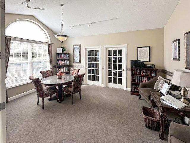 carpeted dining area featuring vaulted ceiling, a textured ceiling, and rail lighting