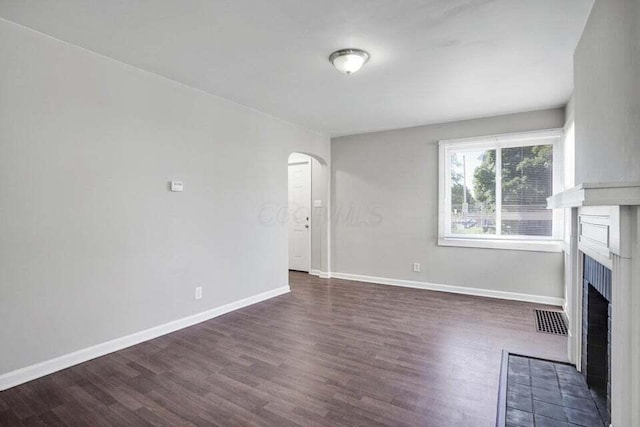 unfurnished living room with a fireplace and dark wood-type flooring