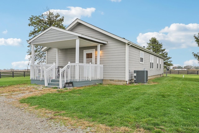 view of front facade featuring a front lawn, covered porch, and central AC