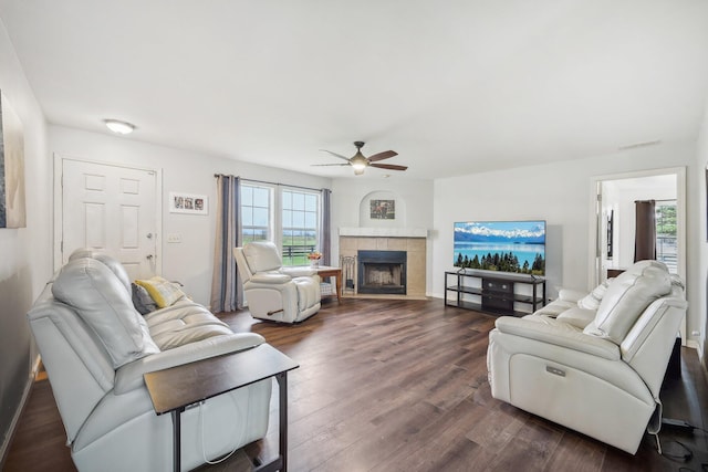 living room featuring a tile fireplace, ceiling fan, and dark wood-type flooring