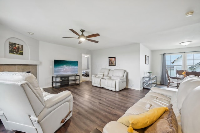 living room featuring ceiling fan, dark wood-type flooring, and a tiled fireplace