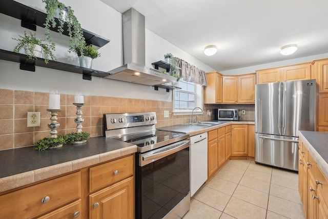 kitchen with sink, wall chimney exhaust hood, decorative backsplash, light tile patterned floors, and appliances with stainless steel finishes