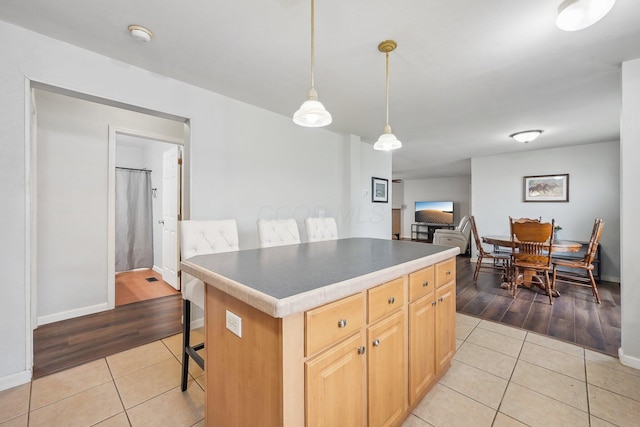 kitchen featuring a breakfast bar area, light brown cabinetry, a center island, and light hardwood / wood-style floors