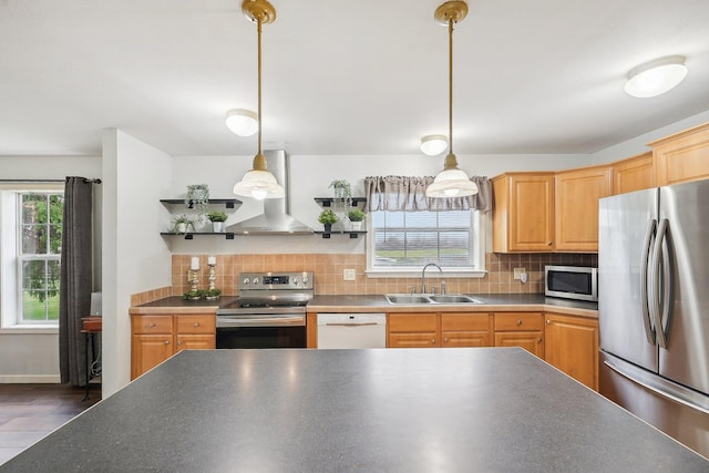 kitchen featuring appliances with stainless steel finishes, pendant lighting, wall chimney exhaust hood, and sink