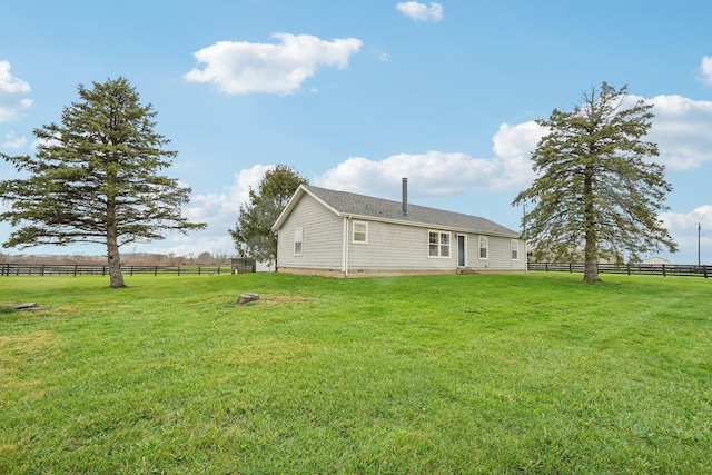 back of property featuring a lawn and a rural view