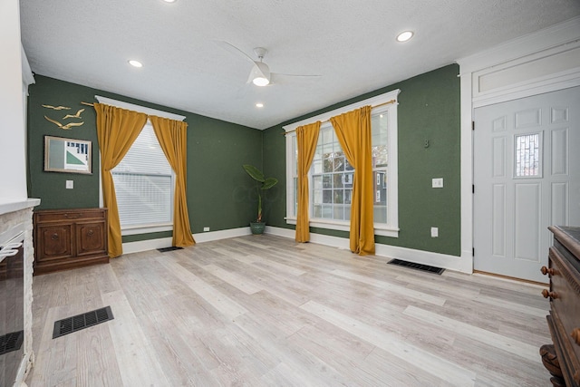 unfurnished living room featuring ceiling fan, a textured ceiling, and light wood-type flooring