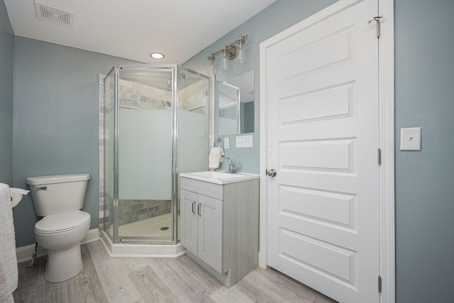 bathroom with hardwood / wood-style floors, vanity, toilet, and a shower with door