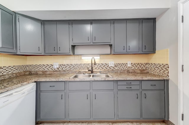 kitchen with white dishwasher, decorative backsplash, gray cabinetry, and sink