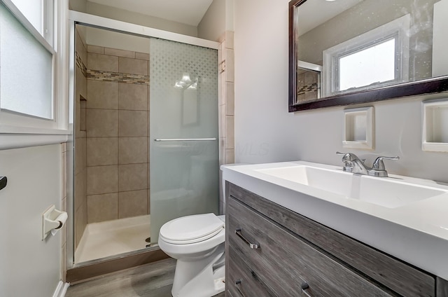 bathroom with a shower with shower door, toilet, wood-type flooring, and vanity