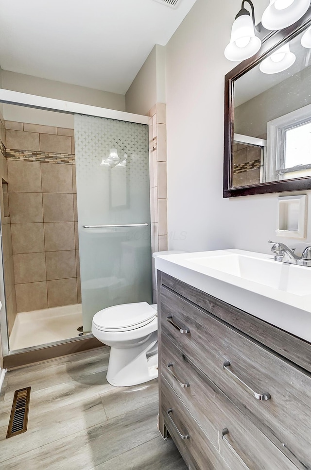 bathroom featuring hardwood / wood-style flooring, toilet, and a shower with shower door