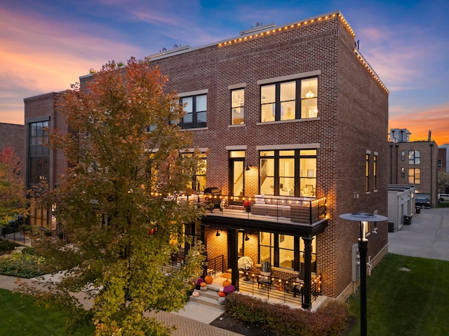 back house at dusk featuring a balcony