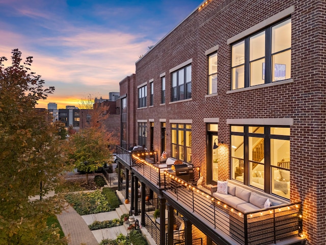 back house at dusk featuring an outdoor living space and a balcony