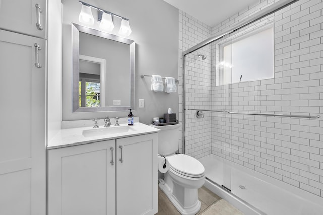 bathroom featuring tile patterned floors, vanity, toilet, and a shower with shower door