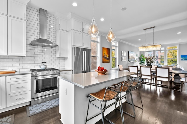 kitchen featuring white cabinets, wall chimney exhaust hood, stainless steel appliances, and a kitchen island