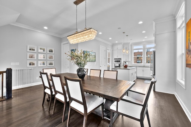 dining room featuring sink, dark hardwood / wood-style flooring, ornamental molding, and an inviting chandelier