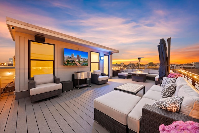 deck at dusk with an outdoor living space with a fire pit