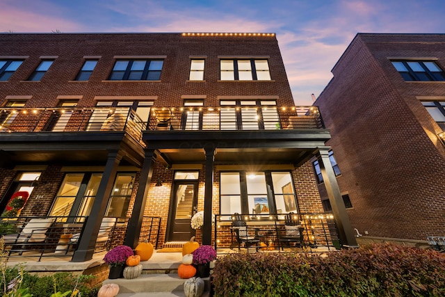 back house at dusk featuring a balcony