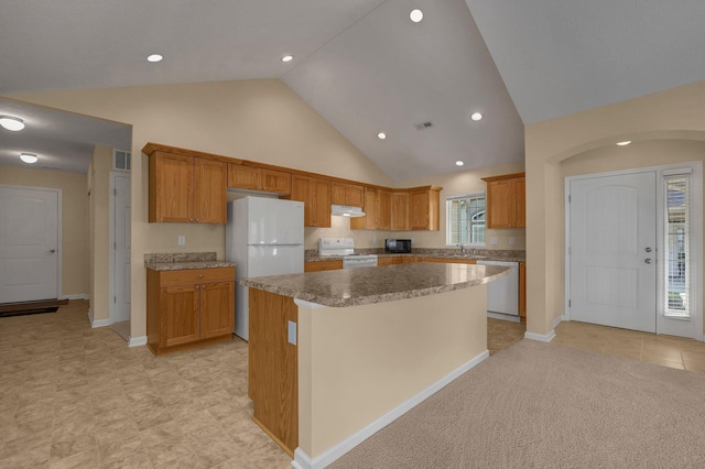 kitchen with plenty of natural light, light carpet, a center island, and white appliances