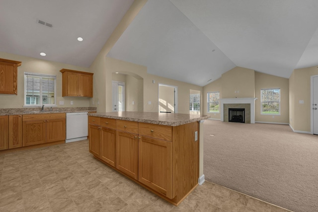 kitchen featuring dishwasher, lofted ceiling, light carpet, sink, and a kitchen island