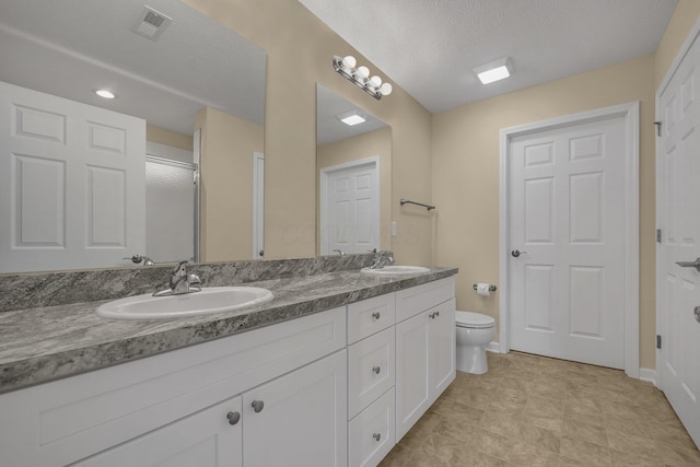 bathroom featuring vanity, toilet, and a textured ceiling