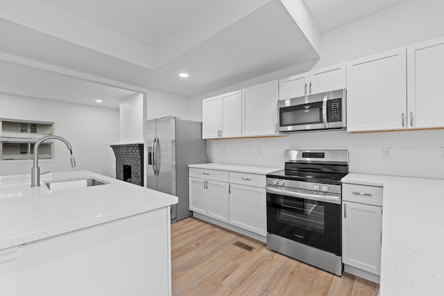 kitchen featuring appliances with stainless steel finishes, light wood-type flooring, white cabinetry, and sink