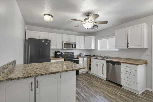 kitchen featuring black appliances, white cabinetry, kitchen peninsula, and dark stone counters