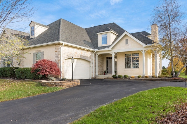 view of front of property featuring covered porch, a garage, and a front yard