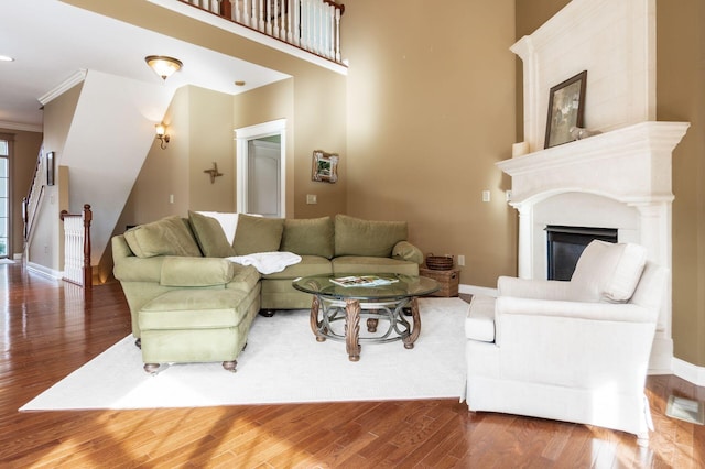 living room featuring a tiled fireplace, wood-type flooring, and ornamental molding