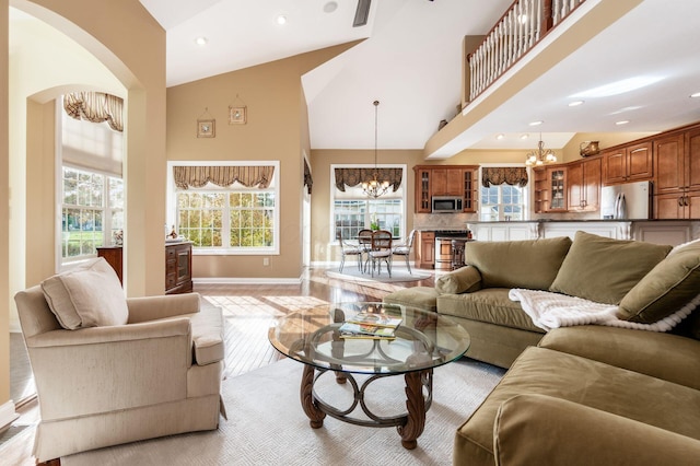 living room featuring an inviting chandelier, light hardwood / wood-style floors, and high vaulted ceiling