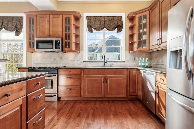 kitchen with sink, tasteful backsplash, dark hardwood / wood-style floors, dark stone countertops, and appliances with stainless steel finishes