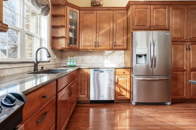 kitchen with stone counters, sink, light hardwood / wood-style flooring, and appliances with stainless steel finishes