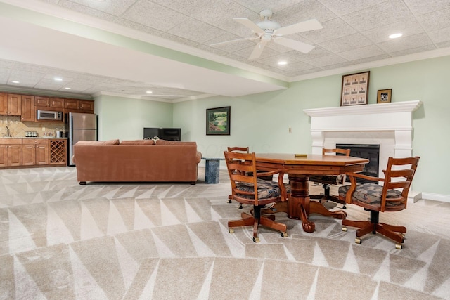 carpeted dining area featuring ceiling fan, sink, and ornamental molding