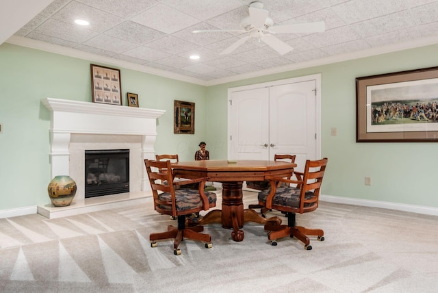 carpeted dining space with ceiling fan and ornamental molding