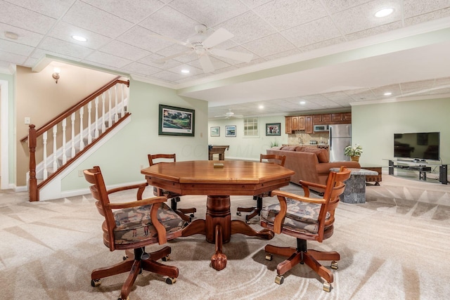 dining room with a paneled ceiling, ceiling fan, and light carpet