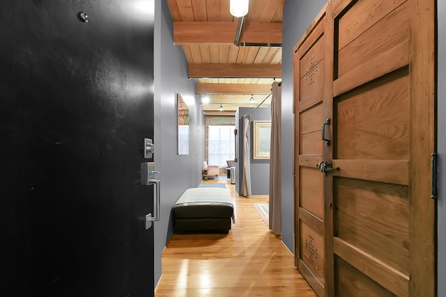 hallway featuring beamed ceiling, light hardwood / wood-style floors, and wood ceiling