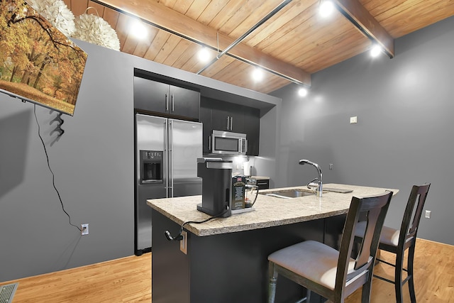 kitchen with beam ceiling, light hardwood / wood-style floors, sink, and appliances with stainless steel finishes