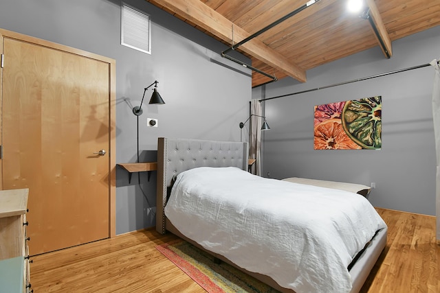 bedroom with beam ceiling, light wood-type flooring, and wooden ceiling