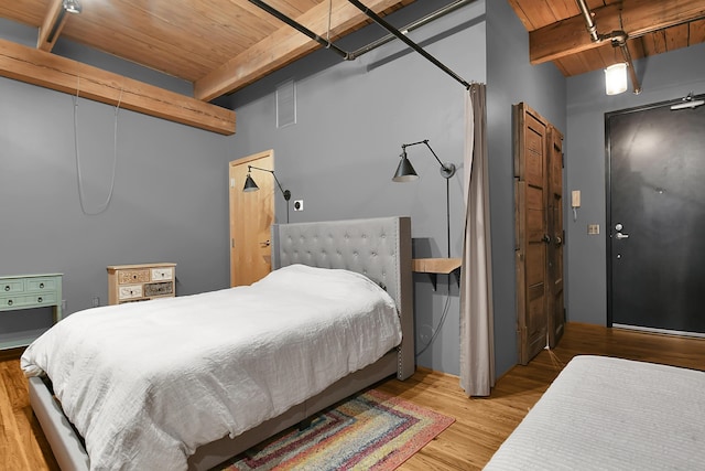 bedroom featuring beamed ceiling, wooden ceiling, and light wood-type flooring