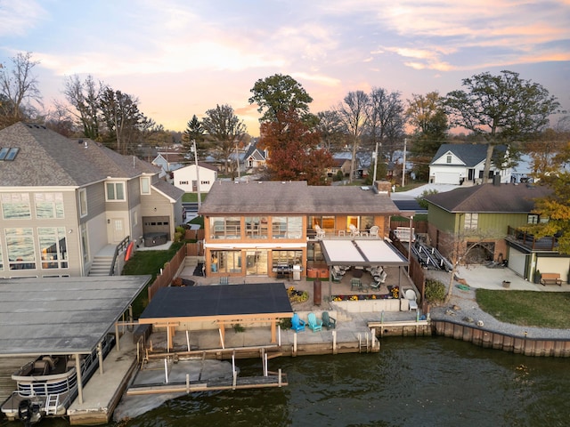 back house at dusk featuring a patio and a water view