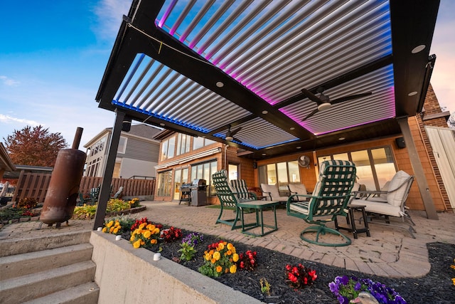 patio terrace at dusk with a pergola, area for grilling, and ceiling fan