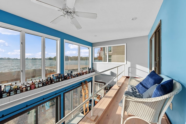 sunroom featuring ceiling fan and a water view