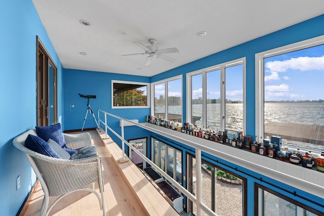 balcony with ceiling fan and a water view