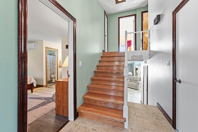 stairs featuring a textured ceiling, hardwood / wood-style floors, and a wall mounted air conditioner