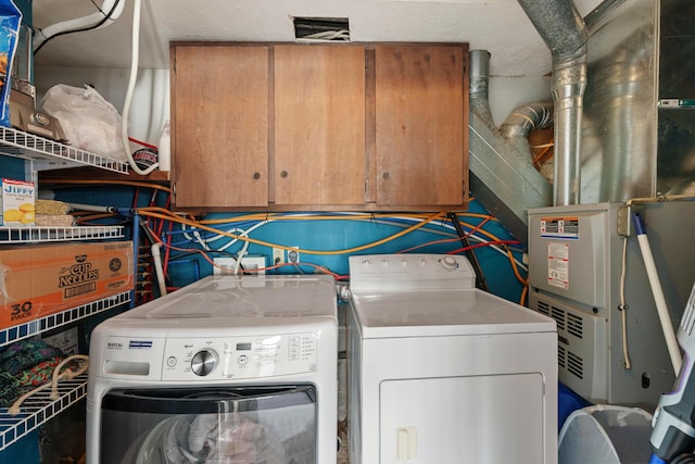 laundry area featuring cabinets, independent washer and dryer, and heating unit