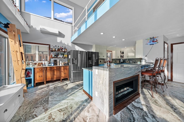 kitchen with backsplash, stainless steel fridge, a towering ceiling, and a healthy amount of sunlight