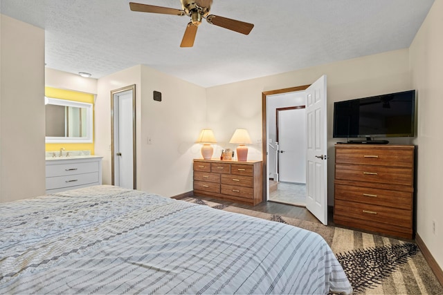 bedroom featuring ensuite bath, a textured ceiling, ceiling fan, sink, and hardwood / wood-style floors