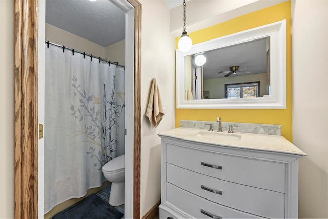 bathroom with vanity, a shower with shower curtain, ceiling fan, toilet, and a textured ceiling