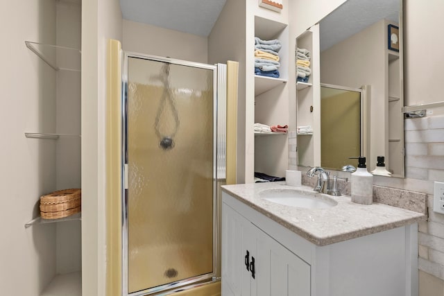 bathroom with vanity, an enclosed shower, and a textured ceiling